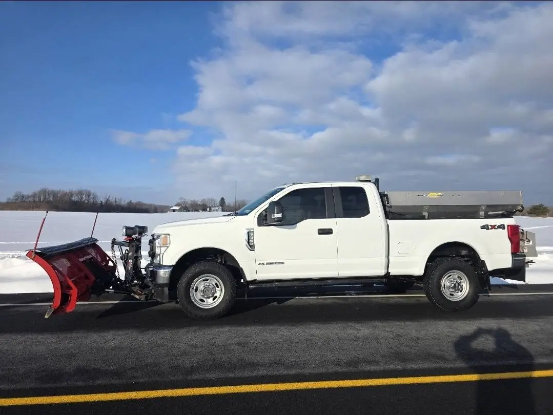 White AAG pickup truck with a red V-plow on a cleared road